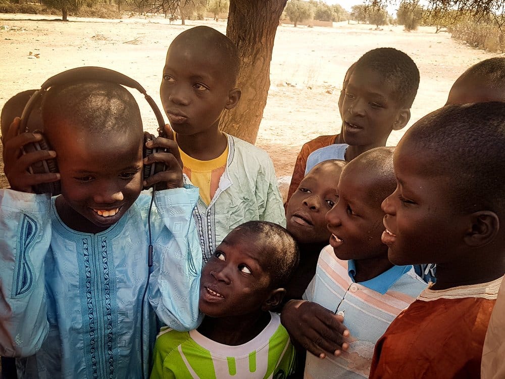 A group of kids huddle around to try on the headphones.