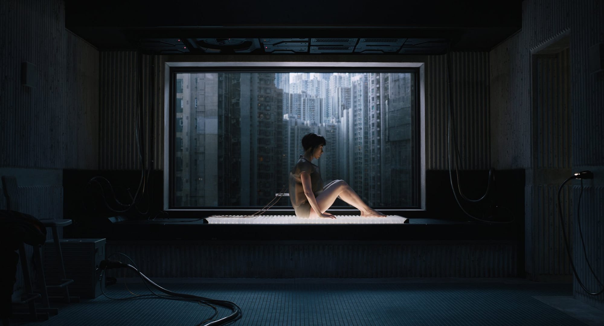 Scarlett Johansson sits up with the dark city showing through her window