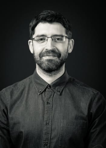 A man with a beard and glasses smiles.