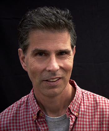 A man with dark hair and a flannel print shirt