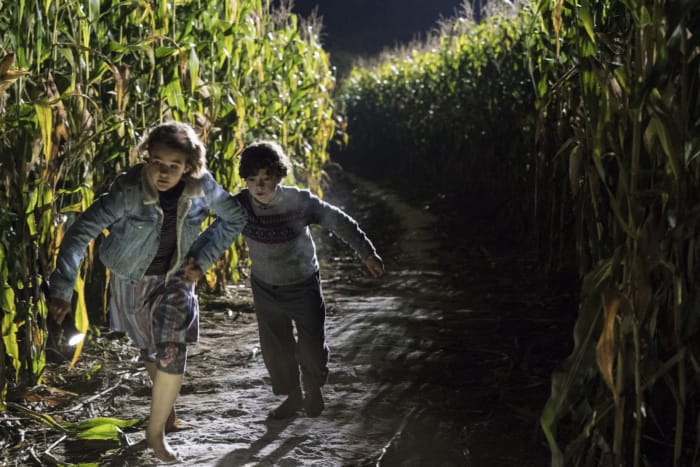 2 concerned children run through a cornfield.