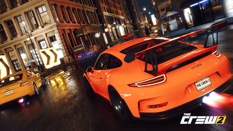 A GT3RS races an Audi at night in a downtown area.