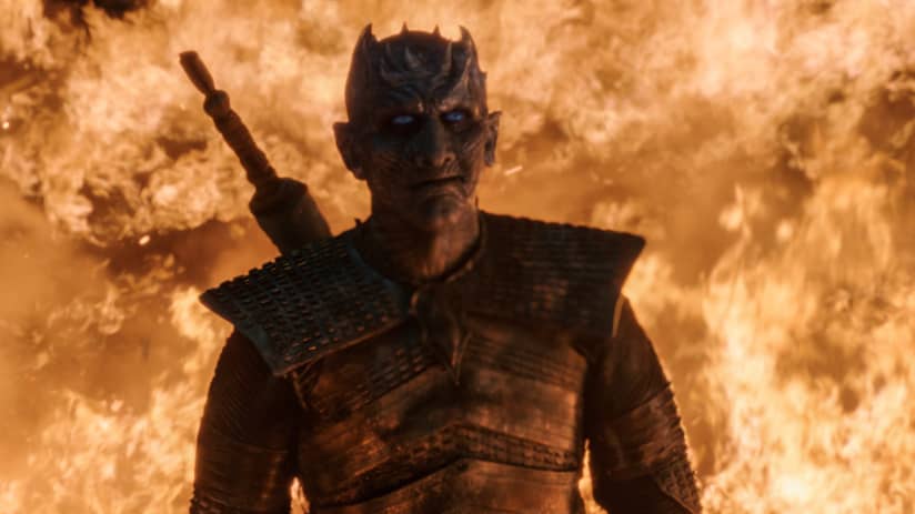 The Night King smiles with fire to his back.