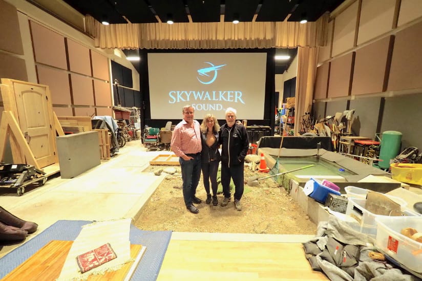 Two men and a women stand in the Skywalker Sound Foley stage sand pit.