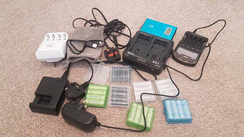 A bunch of batteries and battery charges sit in a pile