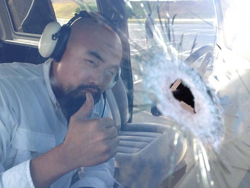 Watson Wu gives a thumbs up next to a bullet hole in the window