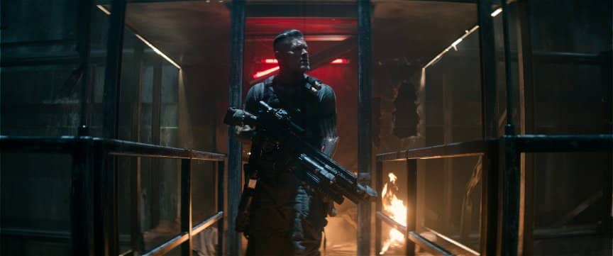Cable searches through a destroyed interior with his massive high-tech submachine gun.