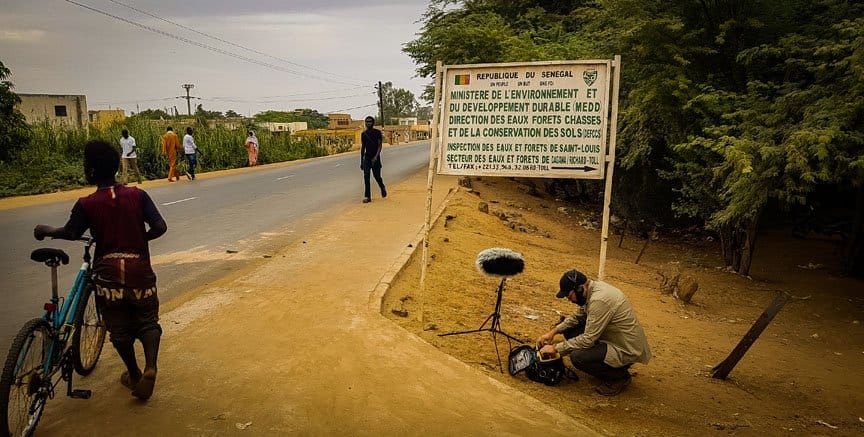 A man recordings pedestrians on a rural road.