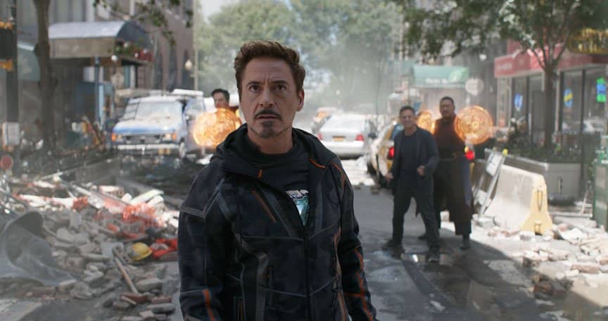 Tony Stark stands in front of Doctor Strange on a crumbled NYC street