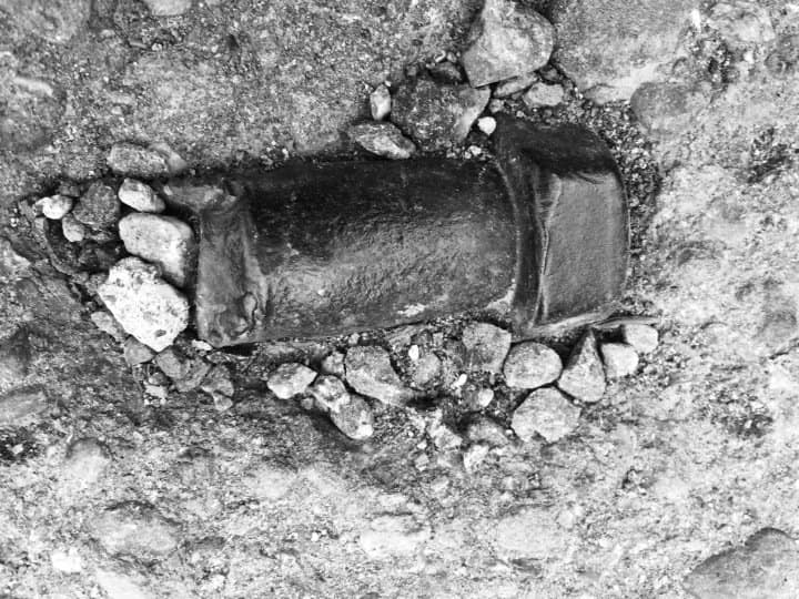 An old metal screw is buried in the ground.