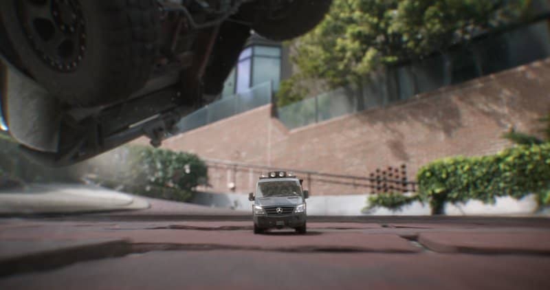 A tiny van speeds along walkway, minuscule in comparison to the bricks.