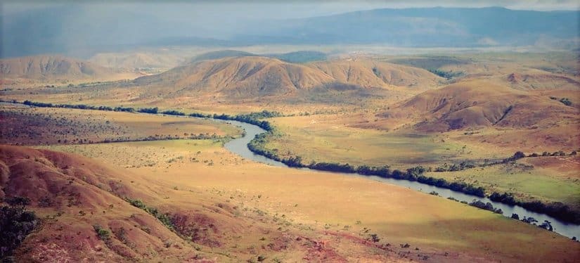 A rolling desolate landscape with a river running through it.