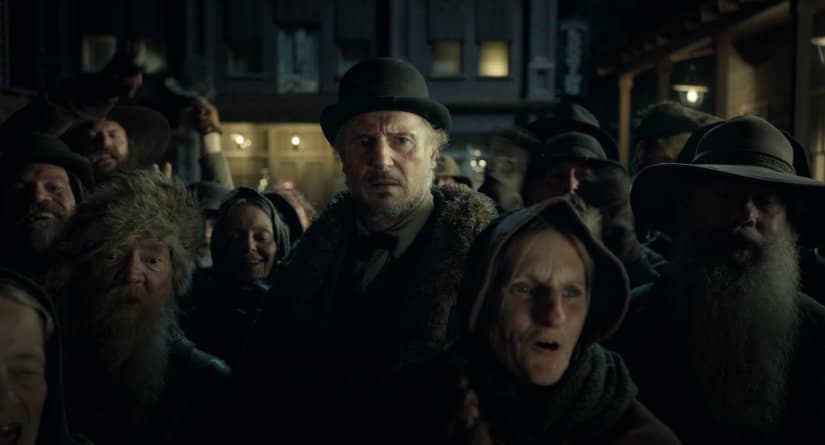 A group of townspeople gather as a taller man looks in concern.