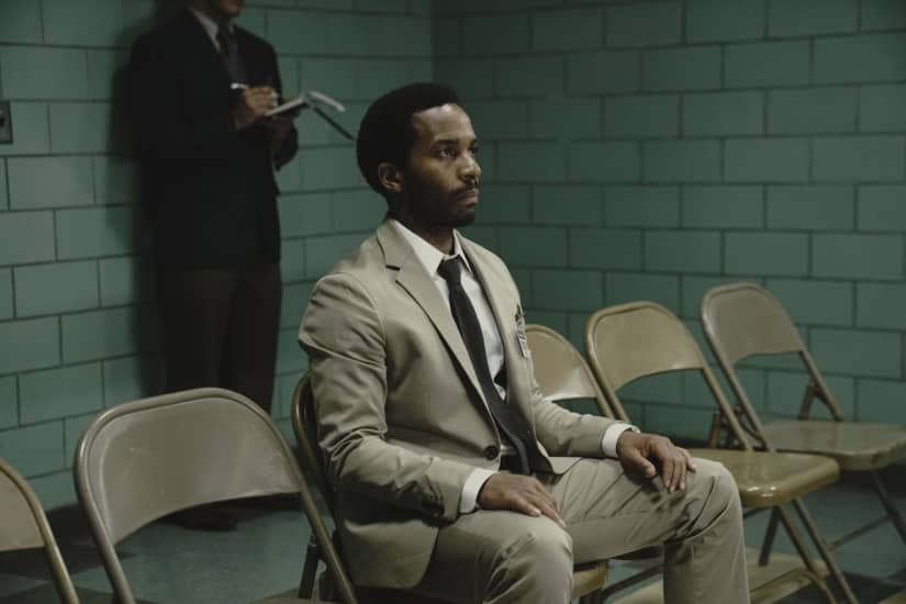 Henry Deaver (Andre Holland) sits in a suit in a prison holding area.