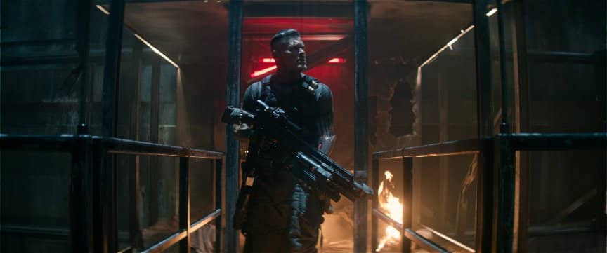 Cable searches through a destroyed interior with his massive high-tech submachine gun.